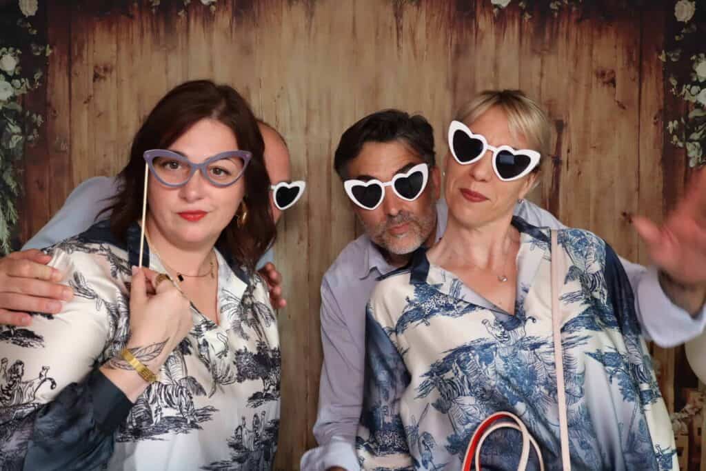Invitées avec des lunettes fantaisie devant un photobooth TurboBooth, décor bois