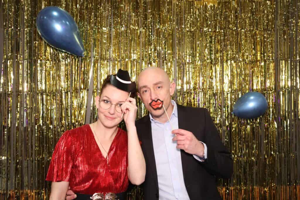 Couple d'invités devant un photobooth TurboBooth, décor doré scintillant