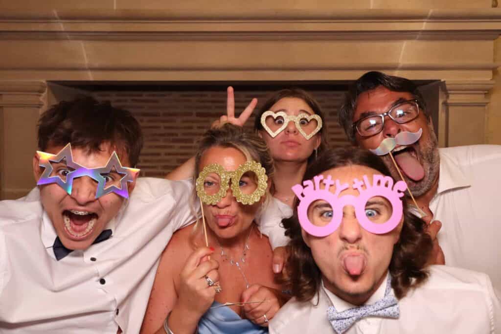 Groupe d'amis avec des accessoires devant un photobooth TurboBooth pendant un mariage