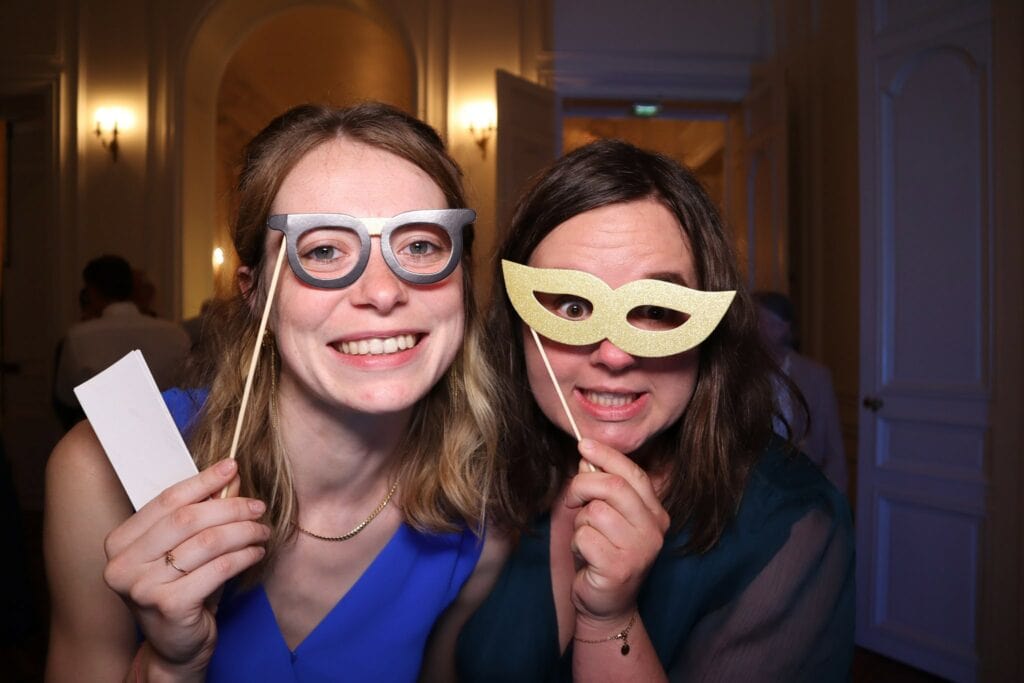 Deux invitées avec des accessoires devant le photobooth