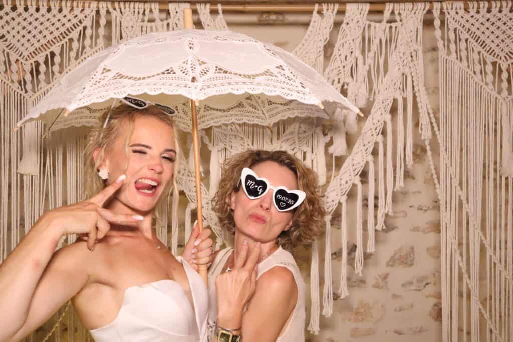 La mariée et une invitée sous une ombrelle